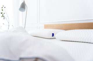 Zwei Sleepi Nackenstützkissen auf einem Bett im hellen Schlafzimmer