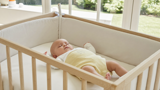 Baby schläft tagsüber friedlich in Rückenlage im Gitterbett ohne Kissen – sicherer Babyschlaf während der Schlafregression